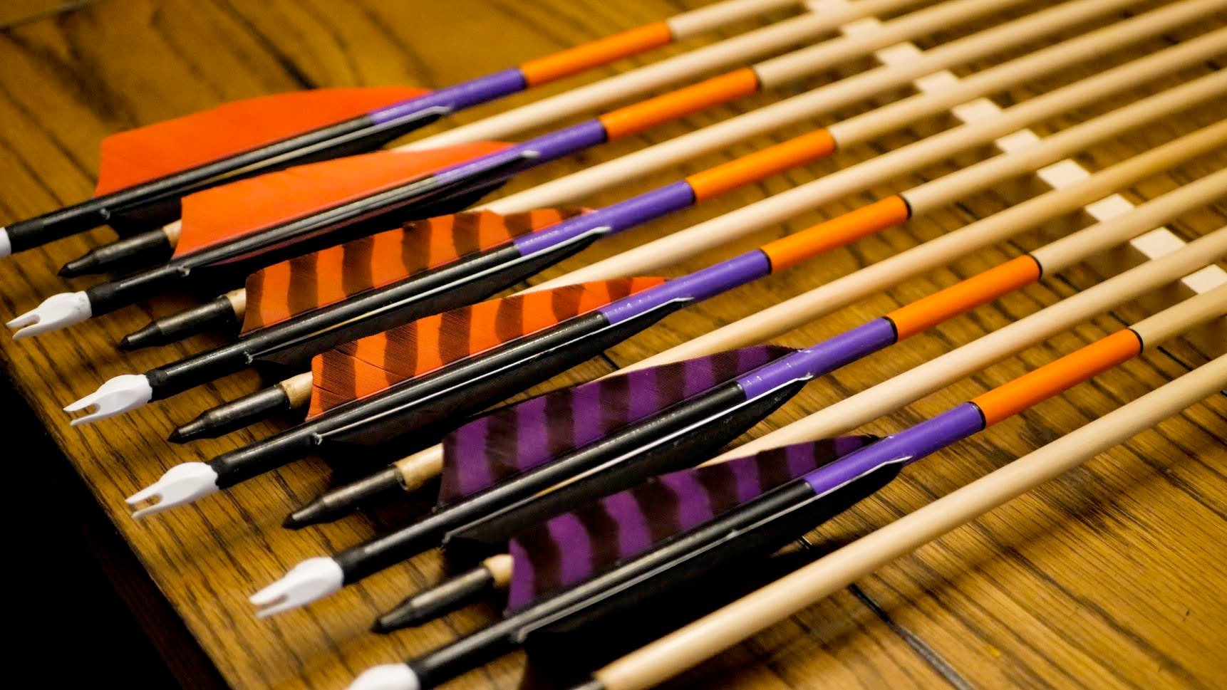 Orange and purple fletched arrows on a drying rack